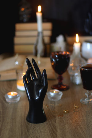 Books, lit candles, red wine, snacks and various deocration on the table. Dark academia or Halloween concept. Selective focus.の写真素材