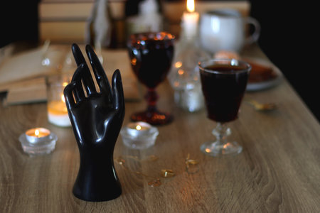 Books, lit candles, red wine, snacks and various decoration on the table. Halloween concept. Selective focus.の写真素材