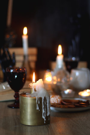 Books, lit candles, red wine, snacks and various deocration on the table. Dark academia or Halloween concept. Selective focus.の写真素材