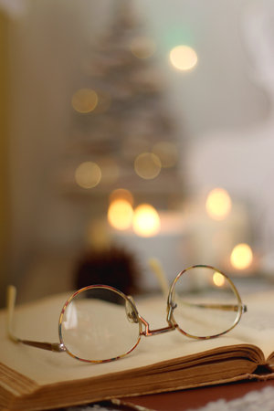 Various Christmas decorations, lit candles, cup of tea or coffee, cookies, books, presents and soft blanket on the table. Holiday hygge at home. Selective focus.の写真素材