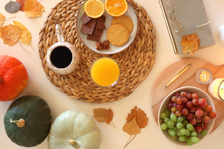 Pumpkins, various food and drinks, fall decorations, books and candles on the table. Fall hygge at...