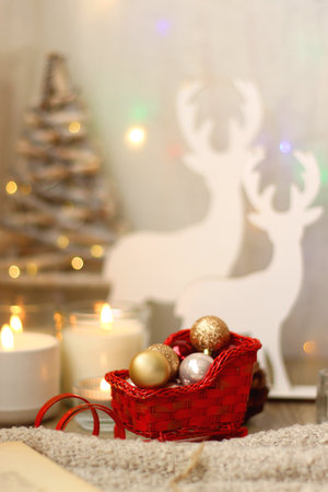 Various Christmas decorations, lit candles, cup of tea or coffee, cookies, books, presents and soft blanket on the table. Holiday hygge at home. Selective focus.の写真素材