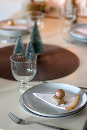 Table set for Christmas meal with plates, glasses, holiday decorations, lit candles and wine. Selective focus.の写真素材