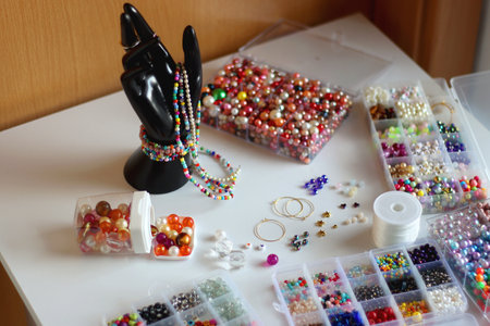Hand figurine, colorful friendship bracelets, necklaces, various beads and DIY supplies on the table. Making jewelry at home. Selective focus.の写真素材