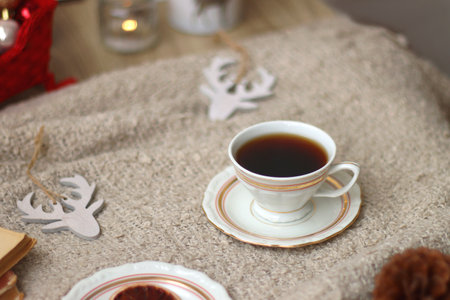 Various Christmas decorations, lit candles, cup of tea or coffee, cookies, books, presents and soft blanket on the table. Holiday hygge at home. Selective focus.の写真素材