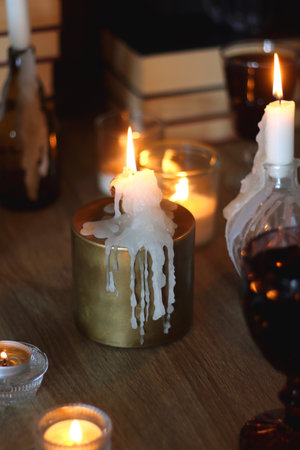 Books, lit candles, red wine, snacks and various deocration on the table. Dark academia or Halloween concept. Selective focus.の写真素材