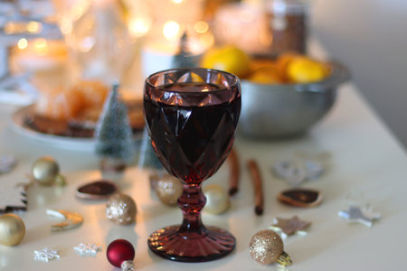 Various Christmas decorations, cookies, chocolate, nuts and tangerines, wine glasses and lit candles on the table. Holiday hygge at home. Selective focus.の写真素材