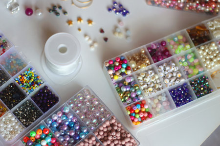 Colorful friendship bracelets, necklaces, various beads and DIY supplies on the table. Making...