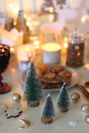 Various Christmas decorations, cookies, chocolate, nuts and tangerines, wine glasses and lit candles on the table. Holiday hygge at home. Selective focus.の写真素材