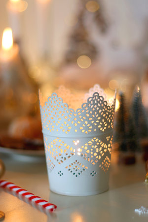 Various Christmas decorations, cookies, chocolate, nuts and tangerines, wine glasses and lit candles on the table. Holiday hygge at home. Selective focus.の写真素材