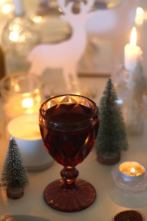 Various Christmas decorations, cookies, chocolate, nuts and tangerines, wine glasses and lit candles on the table. Holiday hygge at home. Selective focus.の写真素材