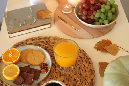 Pumpkins, various food and drinks, fall decorations, books and candles on the table. Fall hygge at home. Selective focus.の写真素材
