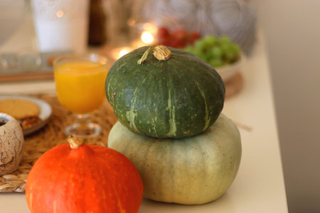 Pumpkins, various food and drinks, fall decorations, books and candles on the table. Fall hygge at home. Selective focus.の写真素材