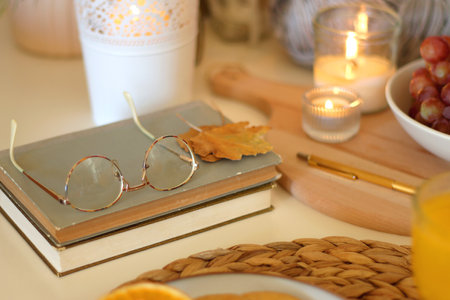 Pumpkins, various food and drinks, fall decorations, books and candles on the table. Fall hygge at home. Selective focus.の写真素材
