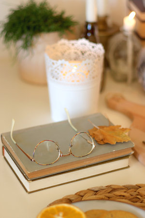 Pumpkins, various food and drinks, fall decorations, books and candles on the table. Fall hygge at home. Selective focus.の写真素材