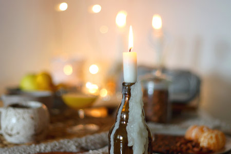 Books, e-reader, tea, orange juice, fruit, snacks, yarn, blanket and lit candles on the table. Autumn or winter at home. Selective focus.の写真素材