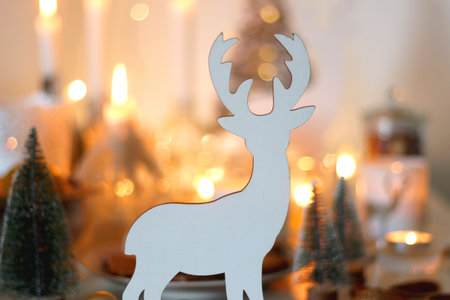 Various Christmas decorations, cookies, chocolate, nuts and tangerines, wine glasses and lit candles on the table. Holiday hygge at home. Selective focus.の写真素材