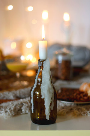Books, e-reader, tea, orange juice, fruit, snacks, yarn, blanket and lit candles on the table. Autumn or winter at home. Selective focus.の写真素材