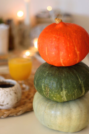 Pumpkins, various food and drinks, fall decorations, books and candles on the table. Fall hygge at home. Selective focus.の写真素材