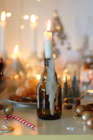 Various Christmas decorations, cookies, chocolate, nuts and tangerines, wine glasses and lit candles on the table. Holiday hygge at home. Selective focus.の写真素材