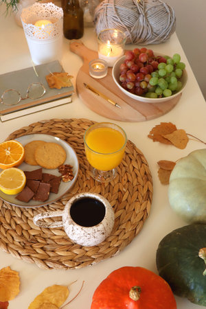 Pumpkins, various food and drinks, fall decorations, books and candles on the table. Fall hygge at home. Selective focus.の写真素材