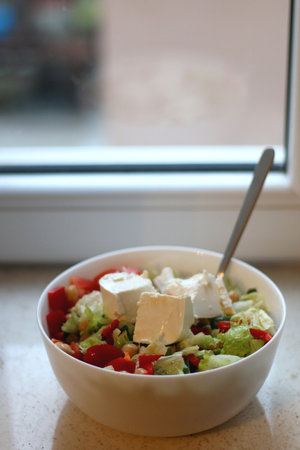 Bowl of tomato, red pepper, lettuce, chickpea and feta cheese salad on the table. Selective focus.の写真素材