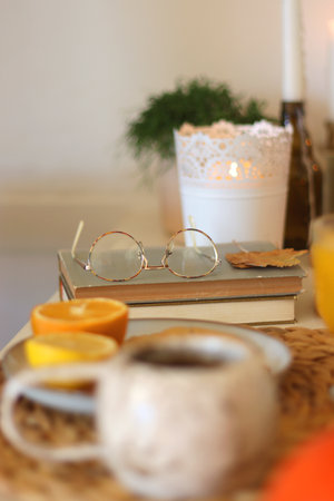 Pumpkins, various food and drinks, fall decorations, books and candles on the table. Fall hygge at home. Selective focus.の写真素材