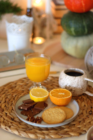 Pumpkins, various food and drinks, fall decorations, books and candles on the table. Fall hygge at home. Selective focus.の写真素材