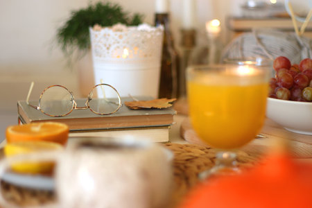 Pumpkins, various food and drinks, fall decorations, books and candles on the table. Fall hygge at home. Selective focus.の写真素材