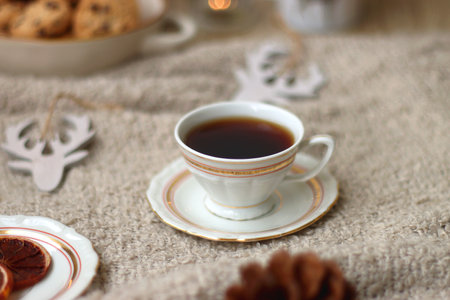 Various Christmas decorations, lit candles, cup of tea or coffee, cookies, books, presents and soft blanket on the table. Holiday hygge at home. Selective focus.の写真素材