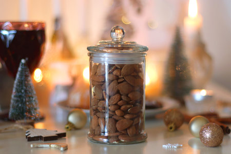 Various Christmas decorations, cookies, chocolate, nuts and tangerines, wine glasses and lit candles on the table. Holiday hygge at home. Selective focus.の写真素材
