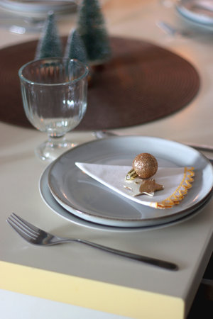 Table set for Christmas meal with plates, glasses, holiday decorations, lit candles and wine. Selective focus.の写真素材