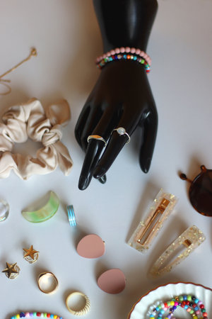 Hand figurine, colorful friendship bracelets, necklaces, various beads and DIY supplies on the table. Making jewelry at home. Selective focus.の写真素材
