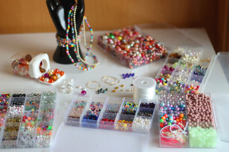 Hand figurine, sunglasses, gold jewelry, colorful bead jewelry, statement rings and various hair accessories on the white table. Selective focus.の写真素材