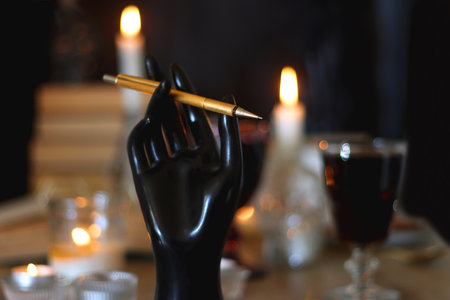 Books, lit candles, red wine, snacks and various decoration on the table. Dark academia or Halloween concept. Selective focus.の写真素材