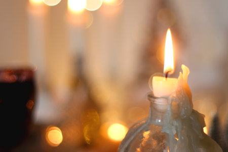 Various Christmas decorations, cookies, chocolate, nuts and tangerines, wine glasses and lit candles on the table. Holiday hygge at home. Selective focus.の写真素材