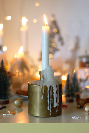 Various Christmas decorations, cookies, chocolate, nuts and tangerines, wine glasses and lit candles on the table. Holiday hygge at home. Selective focus.の写真素材