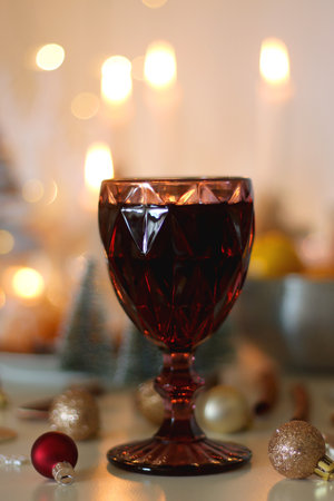 Various Christmas decorations, cookies, chocolate, nuts and tangerines, wine glasses and lit candles on the table. Holiday hygge at home. Selective focus.の写真素材