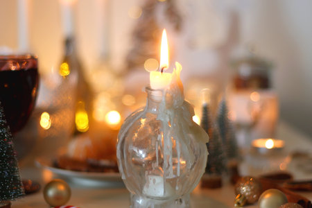 Various Christmas decorations, cookies, chocolate, nuts and tangerines, wine glasses and lit candles on the table. Holiday hygge at home. Selective focus.の写真素材