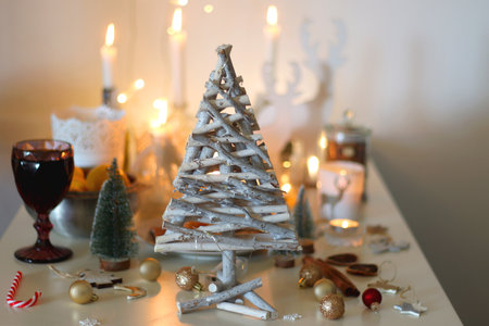 Various Christmas decorations, cookies, chocolate, nuts and tangerines, wine glasses and lit candles on the table. Holiday hygge at home. Selective focus.の写真素材