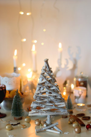 Various Christmas decorations, cookies, chocolate, nuts and tangerines, wine glasses and lit candles on the table. Holiday hygge at home. Selective focus.の写真素材