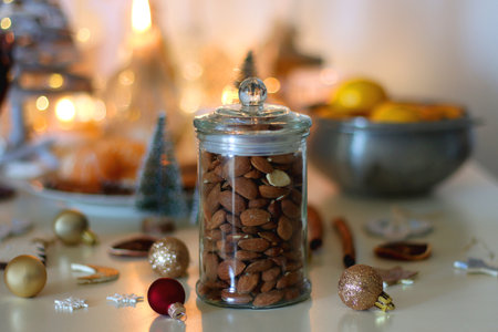 Various Christmas decorations, cookies, chocolate, nuts and tangerines, wine glasses and lit candles on the table. Holiday hygge at home.の写真素材