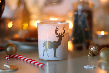 Various Christmas decorations, cookies, chocolate, nuts and tangerines, wine glasses and lit candles on the table. Holiday hygge at home. Selective focus.の写真素材