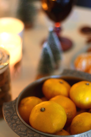 Various Christmas decorations, cookies, chocolate, nuts and tangerines, wine glasses and lit candles on the table. Holiday hygge at home.の写真素材