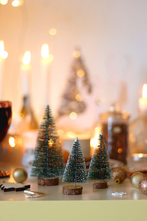 Various Christmas decorations, cookies, chocolate, nuts and tangerines, wine glasses and lit candles on the table. Holiday hygge at home. Selective focus.の写真素材