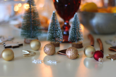 Various Christmas decorations, cookies, chocolate, nuts and tangerines, wine glasses and lit candles on the table. Holiday hygge at home. Selective focus.の写真素材