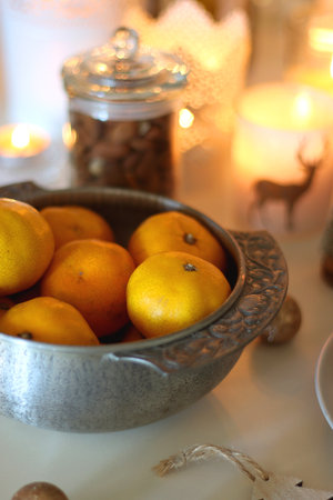 Various Christmas decorations, cookies, chocolate, nuts and tangerines, wine glasses and lit candles on the table. Holiday hygge at home. Selective focus.の写真素材