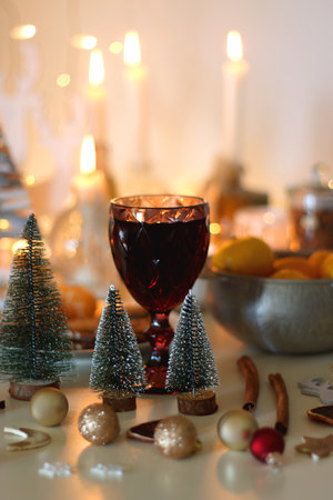 Various Christmas decorations, cookies, chocolate, nuts and tangerines, wine glasses and lit candles on the table. Holiday hygge at home. Selective focus.の写真素材