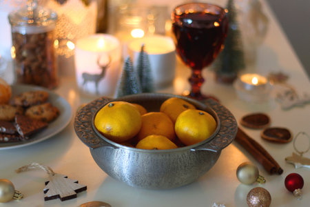Various Christmas decorations, cookies, chocolate, nuts, wine glasses and lit candles on the table. Holiday hygge at home. Selective focus.の写真素材