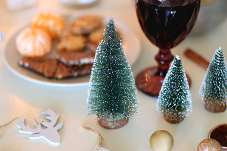 Various Christmas decorations, cookies, chocolate, nuts and tangerines, wine glasses and lit candles on the table. Holiday hygge at home. Selective focus.の写真素材